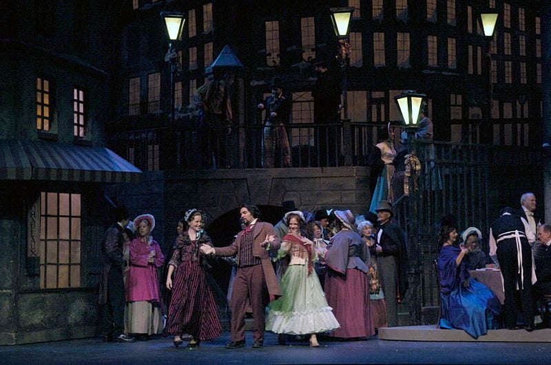 The image shows opera singers performing a scene from La Boheme .
