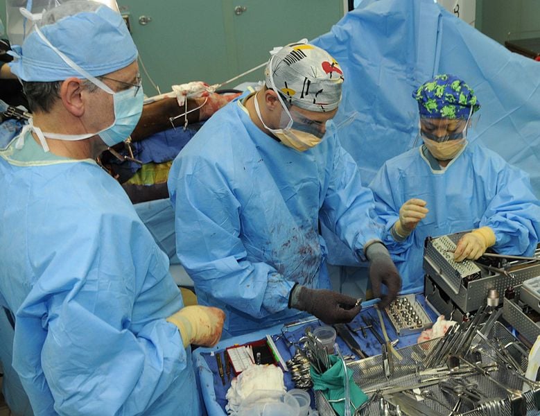 The image shows three surgeons conducting a surgical procedure.