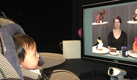 The image shows a baby watching TV.