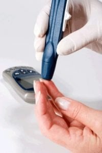 The image shows a patient undergoing a pin prick blood test for diabetes.