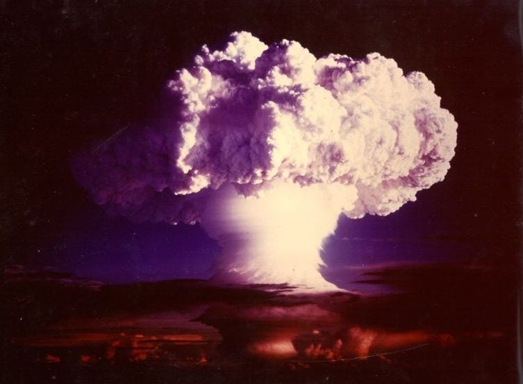 The image shows a mushroom cloud from a nuclear bomb test.
