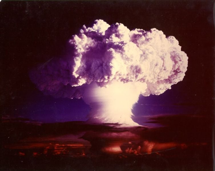 The image shows a mushroom cloud from a nuclear bomb test.