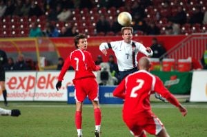The image shows a football player going to 'header' a ball during a Poland versus US friendly soccer game.