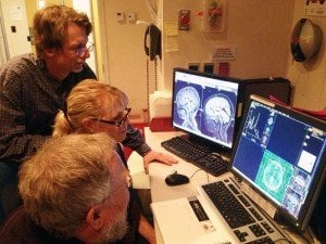 The image shows the researcher reviewing brain scans associated with the research.