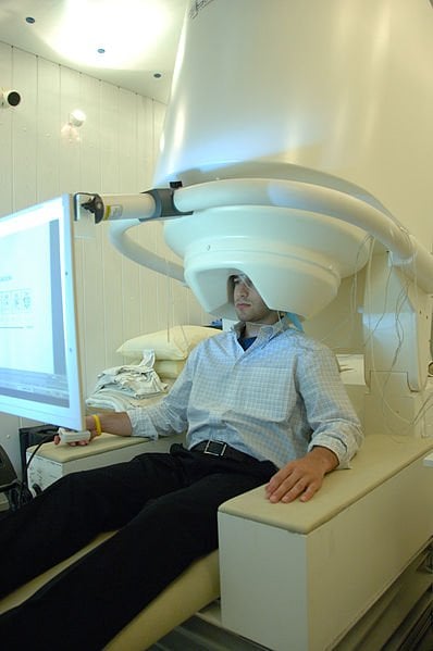 The image shows a person undergoing a MEG scan.