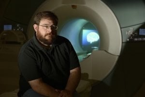 This image shows lead researcher, Stephen LaConte sitting in front of the fMRI machine.
