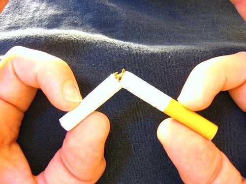 The image shows a person breaking a cigarette.