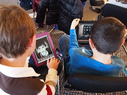 The image shows children using an ipad.