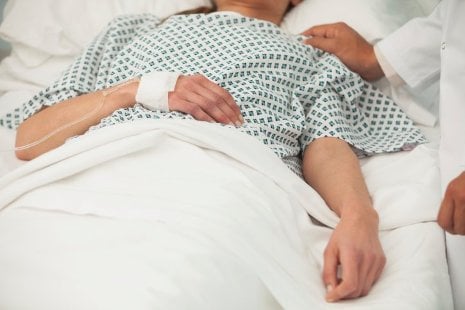 The image shows a person in a hospital bed.