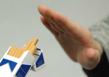 The image shows a person refusing a cigarette from a packet.
