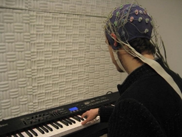 The image shows a person playing a piano wearing an eeg.