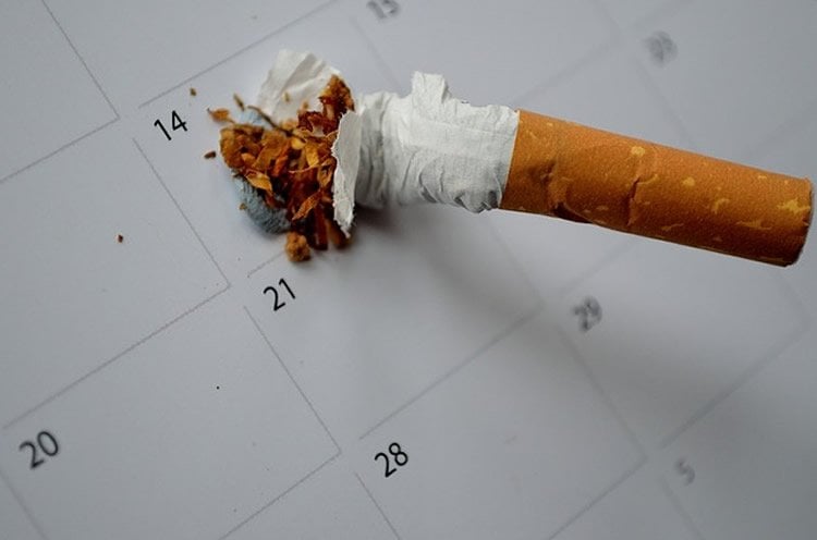 The image shows a stubbed out cigarette on a calender.