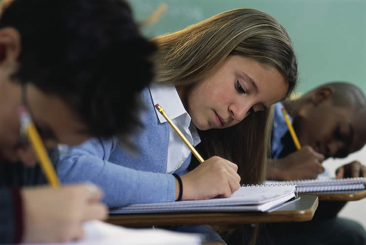 The image shows two children writing in school books.