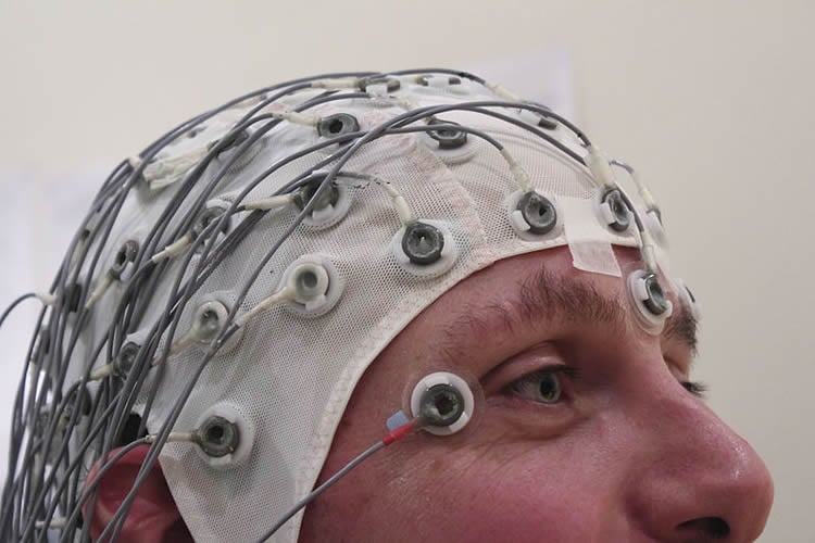The image shows the top of a man's head. He is wearing an EEG cap.