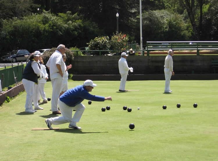 This image shows a group of older people playing lawn bowls.