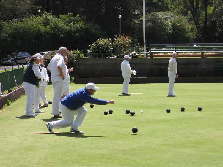 This image shows a group of older people playing lawn bowls.