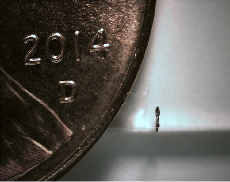 This image shows a side view of the microbot next to a penny.