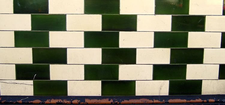 The image shows the tiled cafe wall. The tiles are places to look as though they are shrinking. They are white and dark green.