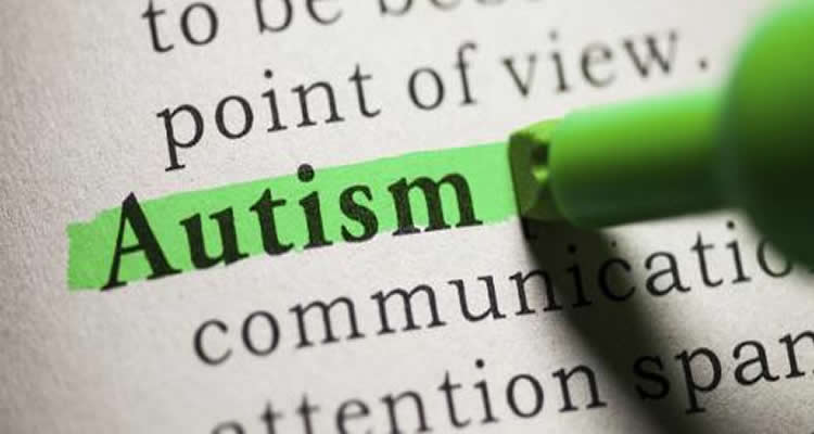 This image shows the word Autism in a dictionary. Someone is highlighting the word with a green highlighter pen.