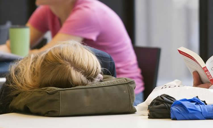 This image shows a teenage girl sleeping on her school bag.