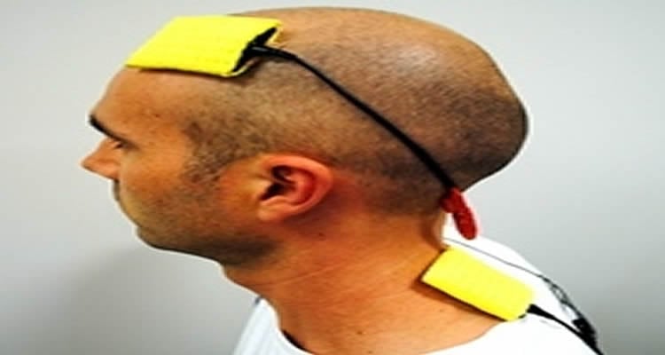 The image shows a person with the tDCS device on his head.