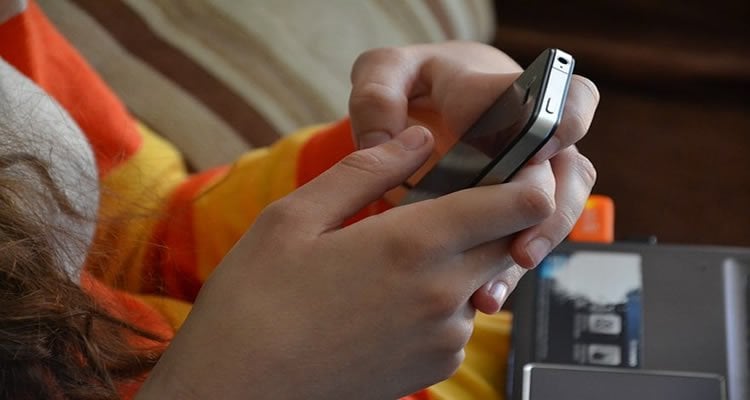 The image shows a smartphone in a person's hands. The person appears to be texting.