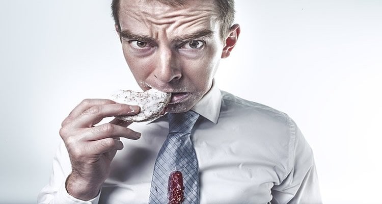 The image shows a stressed looking man eating a sweet donut.