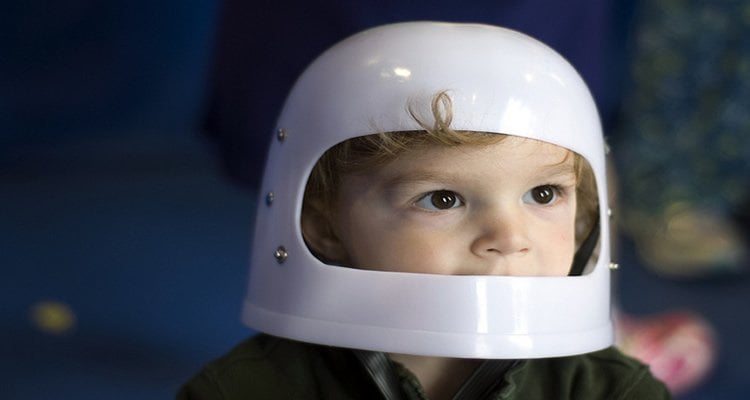The image shows a young child with a plastic astronaut helmet on his head.