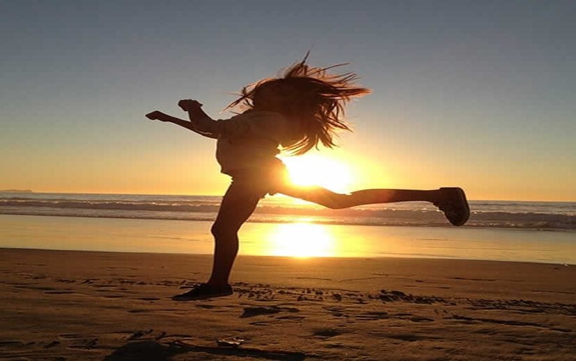 The image shows a girl jumping on a beach.