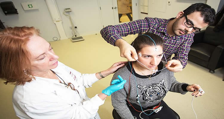 This is a photo showing the researchers fitting a test paticipant with the EEG headpiece.