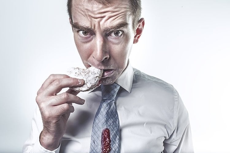 This image shows a man eating a cookie and looking guilty.