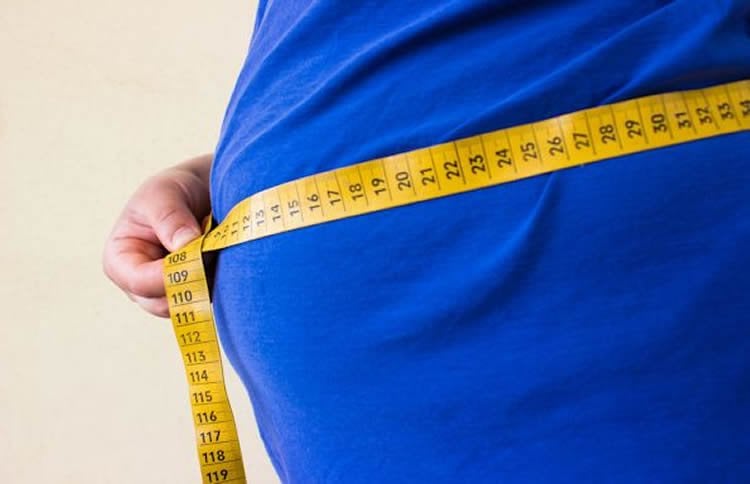This image shows an overweight man's tummy with a measuring tape around it.