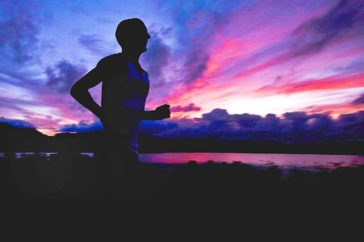 Photo of a man running against a sunset background.