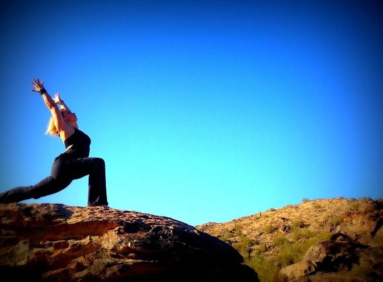 Image of a woman in a yoga pose against a blue sky backdrop.