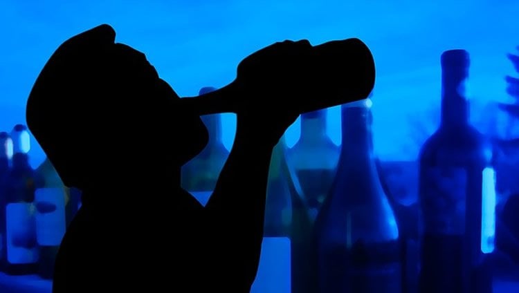 Shadowy image of a man drinking from a bottle.