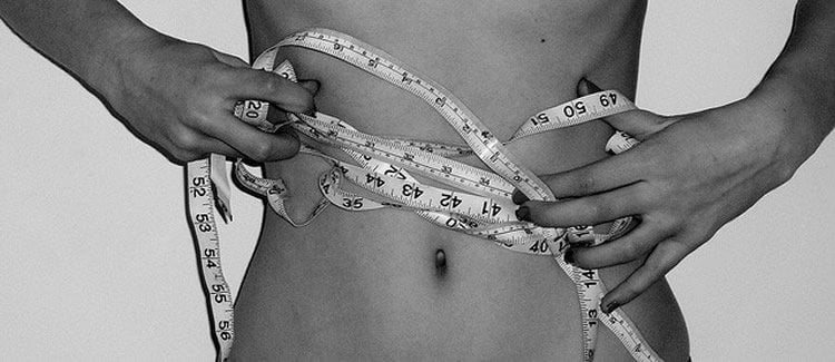 Photo of woman's waist and measuring tape.