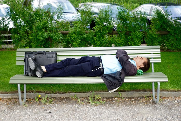 Photo of a business man sleeping on a bench.