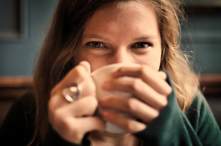 Image shows a woman drinking a cup of coffee.