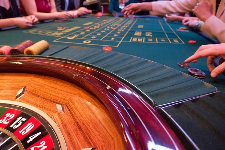 Image shows people gambling around a roulette table.