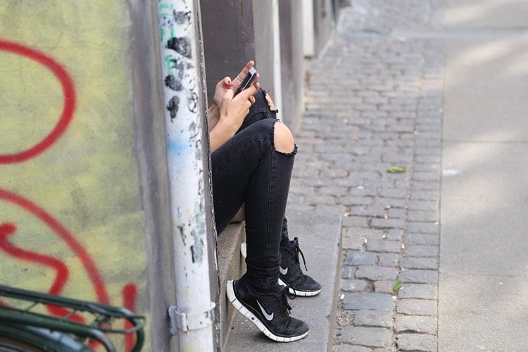 Image shows a girl search on a cell phone.