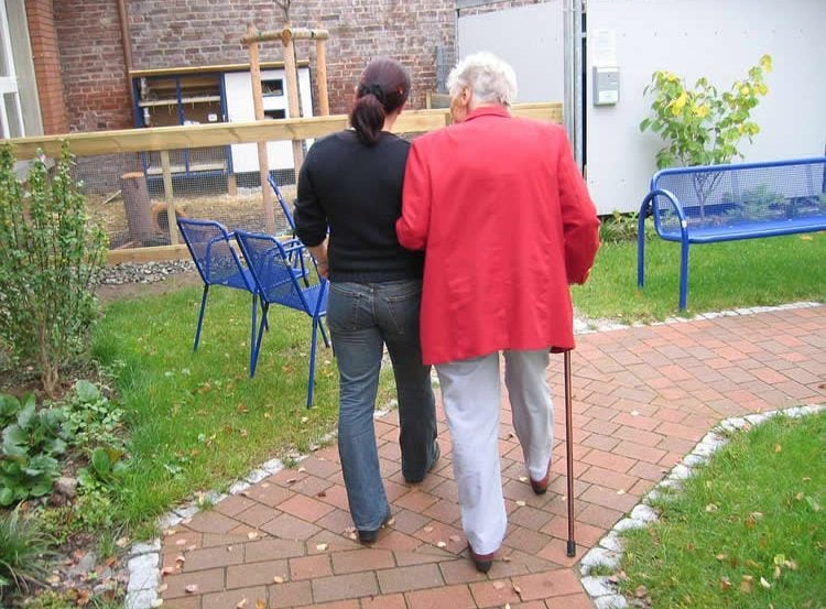 Image shows an old and young woman walking together.