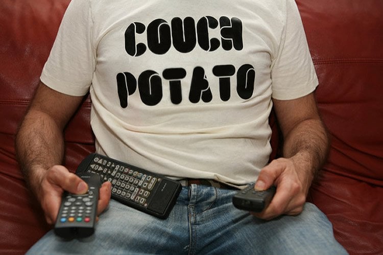 Image shows a person sitting on a couch with a t-shirt that reads couch potato.