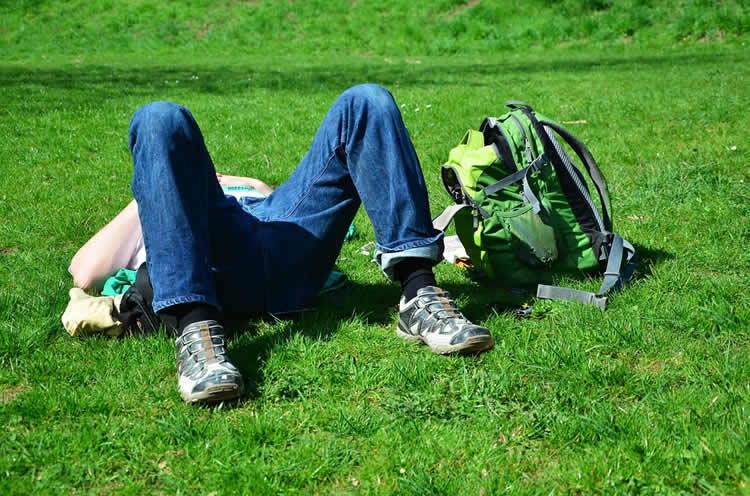Image shows a teenage boy sleeping on the grass.