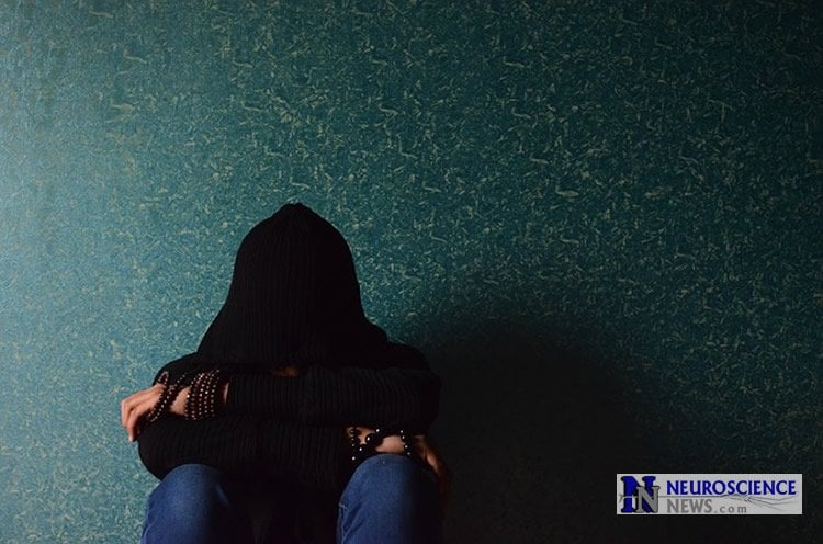 Image of a depressed man sitting next to a wall.