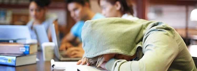 Image shows a teen sleeping at a desk.