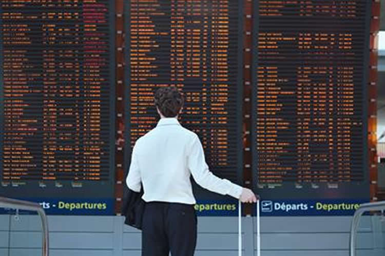 Image shows a man looking at a train departure board.