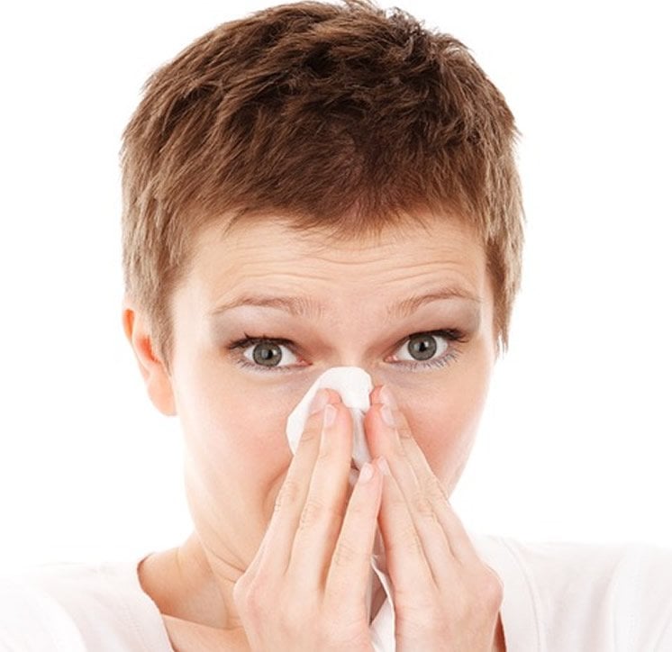 Image shows a woman sneezing.