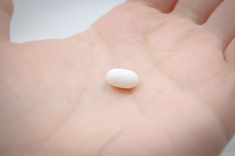 Image shows a pill in a person's hand.