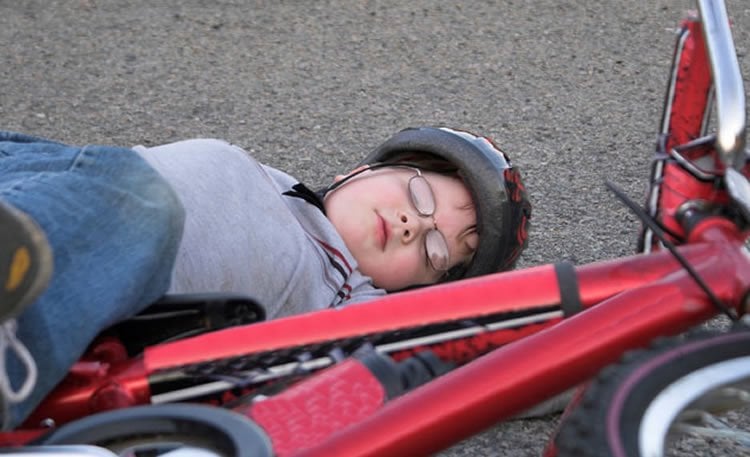 Photo of a child laying next to a bike.