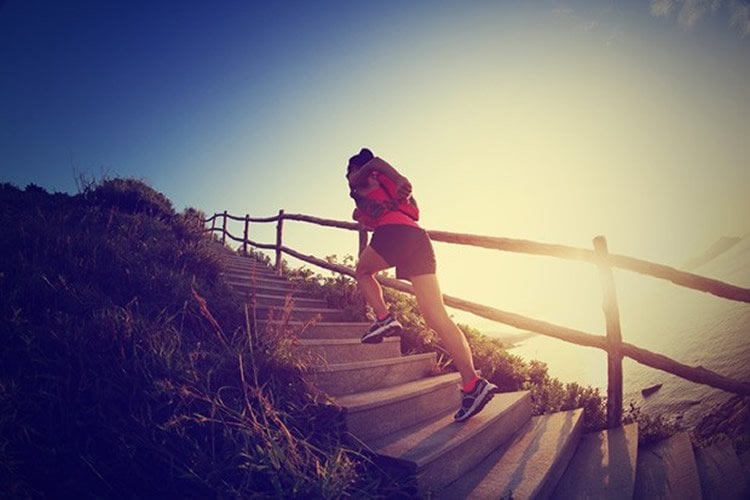 Image shows a woman running up steps on a beach.